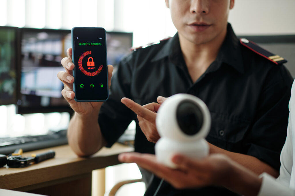 Security guard demonstrates a new security control application for smartphones to a manager, illustrating Security Camera Installation services for comprehensive surveillance and security solutions.