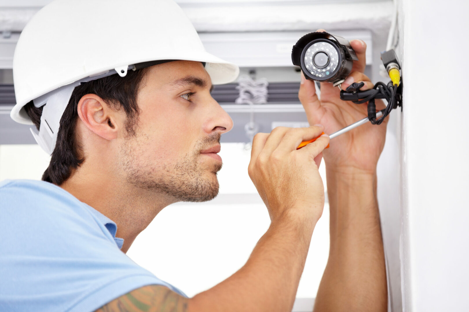 Handsome young man installing a security camera, highlighting Security Camera Installation services for effective home or business surveillance setup.